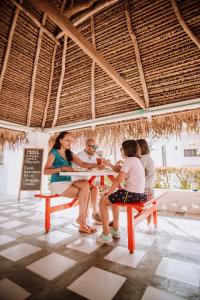 un grupo de personas sentadas en un banco en un restaurante en Hotel Bungalows Marbella Costa Esmeralda, en Monte Gordo