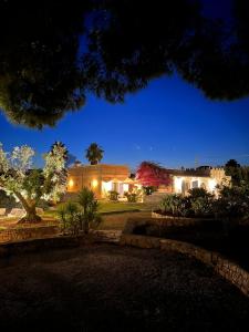 uma casa com luzes acesas num quintal à noite em La Monacedda - Country Boutique Apartments - Villa Laura Ostuni em Ostuni