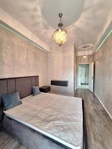 Un dormitorio con una cama grande y una lámpara de araña. en TZ en Baku