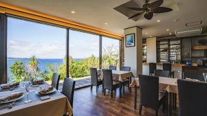 Un restaurante con mesas y sillas y un gran ventanal. en KAYA RESORT KOURIJIMA - Vacation STAY 94979v, en Kouri
