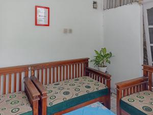 a bedroom with two beds and a plant on the wall at RedDoorz Syariah near RSUD Karawang 2 in Karawang