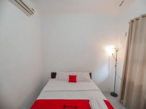 a bedroom with a white bed with a red pillow at RedDoorz Syariah near RSUD Karawang 2 in Karawang