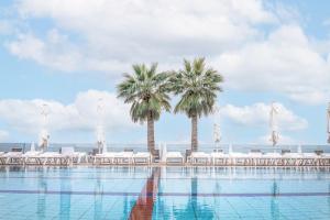 ein Swimmingpool mit Palmen und weißen Stühlen in der Unterkunft Golan Hotel in Tiberias + 18 Fotos