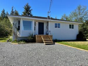 a small white house with a porch and a staircase at Sunrise Mountain view Skidegate House 