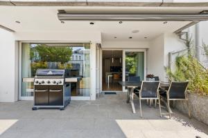 an outdoor patio with a grill and a table and chairs at The R Apartment Uetliberg, Klima, Parken - Wallbox in Geroldswil