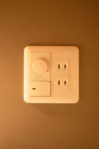 a white lightswitch on a wall with a camera at LOCOMOTION COFFEE AND BED in Tateyama