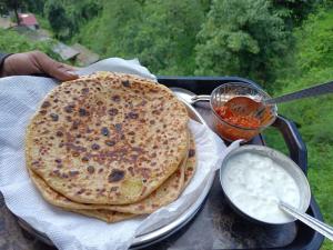 a tray with a plate of chapati and a bowl of dip at 100 stairs holiday home in Mussoorie