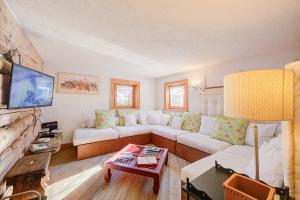 a living room with a white couch and a tv at Chalet Lidia Ski in-Ski out 50m - Happy Rentals in Livigno