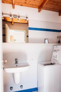 un piccolo bagno bianco con lavandino e lavatrice di JAJA Studios Paros a Paroikia