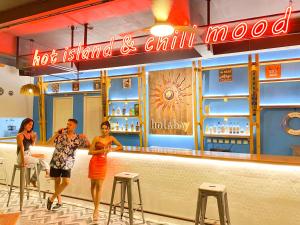 a group of people standing at a bar in a restaurant at Holabay Resort in Panglao Island