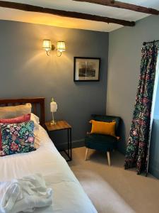 a bedroom with a bed and a chair at Blairbeg Cottage in Blairgowrie