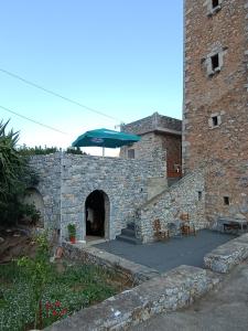 a stone building with a table and an umbrella at pyrgospito in Éxo Nímfion