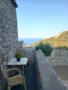 a table and chairs on the side of a stone building at pyrgospito in Éxo Nímfion