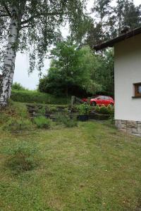 a yard with a fence and a red car in the background at Chata Žár in Žár