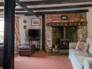 a living room with a stone fireplace and a tv at Rose Thatch in Kingsbridge