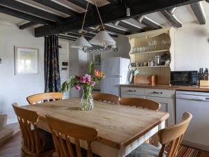 a kitchen with a wooden table with a vase of flowers on it at Rose Thatch in Kingsbridge