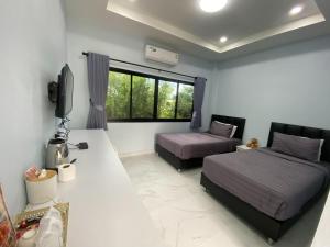 1 dormitorio con 2 camas y TV. en I AM Cottage เฮือนแก้วมณี, en Nakhon Pathom