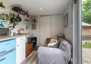 ein Wohnzimmer mit einer Couch in einem winzigen Haus in der Unterkunft Hattie the Horse Box in Hawkhurst