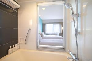 ein Bad mit einer Badewanne und einem Spiegel in der Unterkunft Holiday Inn Osaka Namba by IHG in Osaka
