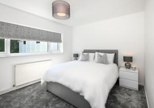 a white bedroom with a large bed and a window at Mor a Mynydd in Abersoch