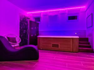 Habitación con iluminación púrpura, silla y escaleras en Residence Del Tellaro en Noto Marina