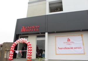 a store front with a sign and a red and white arch at Ixoras Hotel Lemba in Kinshasa