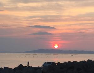 een persoon op het strand die naar de zonsondergang kijkt bij オーベルジュ鳴門 in Naruto