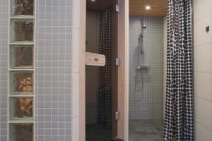 baño con paredes de azulejos azules y ducha. en Aurora Cabin en Kiruna