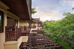 Un balcón de una casa con escaleras de madera en Anantara Xishuangbanna Resort, en Jinghong