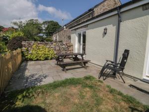 a patio with a wooden picnic table and two chairs at No 3 The Dairy in Llangefni