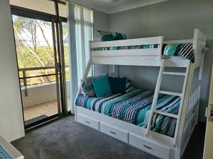 a bedroom with two bunk beds with a balcony at The Commodore, 23,9-11 Donald Street - Delightful unit with gorgeous water views, air con and wi-fi in Nelson Bay