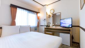 東京にある東横INN蒲田東口のベッド、デスク、テレビが備わるホテルルームです。