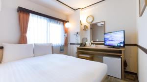 a hotel room with a bed and a desk with a television at Toyoko Inn Tokyo Kamata Higashi-guchi in Tokyo
