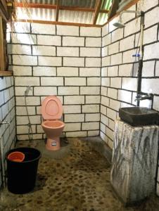 a bathroom with a pink toilet in a brick wall at Sumilir Riverside Retreat in Banyuwangi