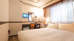 大阪市にある東横INN新大阪中央口本館の白いベッドと窓が備わるホテルルームです。
