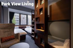 a room with a chair and a bed and a window at COCOSHUKU Shinjuku-Hanazono in Tokyo