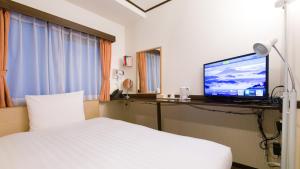 大阪市にある東横INN新大阪中央口本館のベッド1台、薄型テレビが備わるホテルルームです。