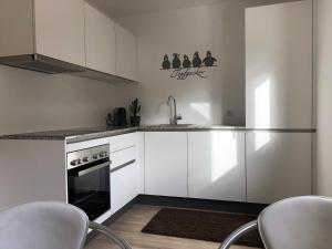 a kitchen with white cabinets and a sink and a stove at Apartments "Am Ardetzenberg" in Feldkirch