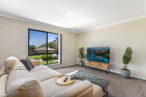 sala de estar con sofá blanco y TV en Terbium Sanctuary, en Brisbane