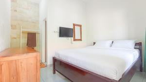 a bedroom with a white bed and a television at Kos Bulan Bali in Kuta