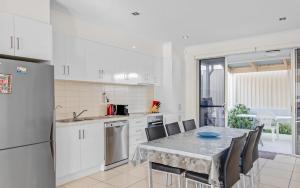 a kitchen with a table with chairs and a refrigerator at No.8 - The Block in Victor Harbor