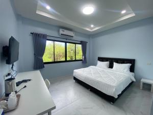 1 dormitorio con cama, escritorio y ventana en I AM Cottage เฮือนแก้วมณี, en Nakhon Pathom