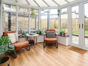 a conservatory with two chairs and a table and windows at Muscle Shoals in Seahouses