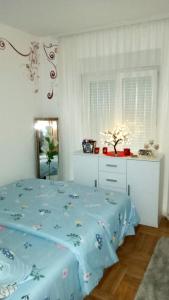 a bedroom with a bed with a blue comforter at PremiumPlus Apartman in Vrnjačka Banja