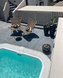 a patio with two chairs and a swimming pool at Aidani Luxurious Rooms in Vóthon