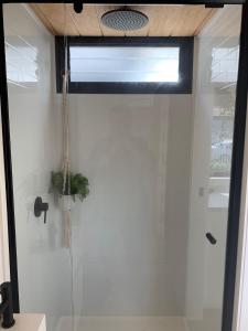 a shower with a glass door in a bathroom at Big Yard Escapes - Two Off-Grid Tiny Houses on the Mowamba River in Jindabyne