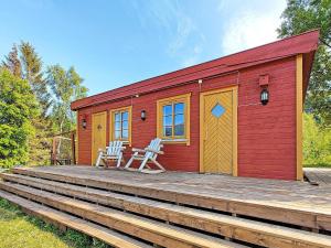 a red cabin with two chairs on a wooden deck at 6 person holiday home in Kviby in Kviby