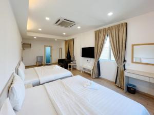 een hotelkamer met 2 bedden en een televisie bij Vvip Hotel in Hutan Melintang