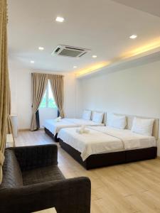una camera d'albergo con due letti e un divano di Vvip Hotel a Hutan Melintang