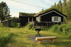 a black house with a grill and a bench at Velfjord Camping & Hytter in Velfjord